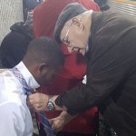Image of couple teaching man how to tie his tie at Atlanta subway station